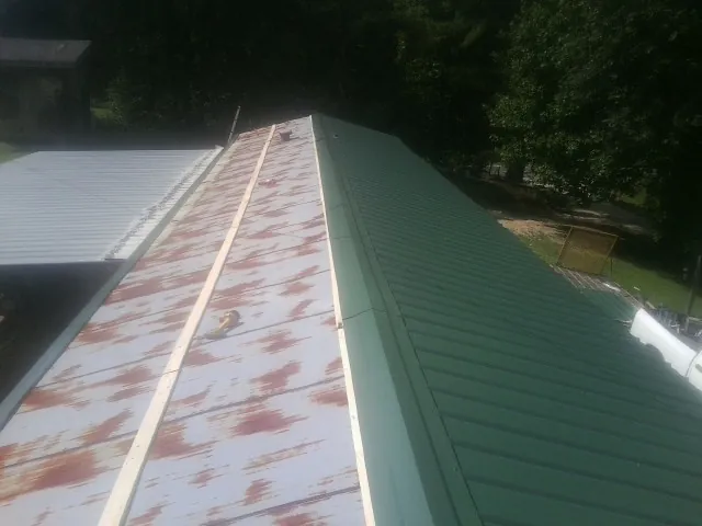 Old rusted panels beside newly installed green metal roofing — Wind Damage Roof Repair by Roofing Brothers in Torrance